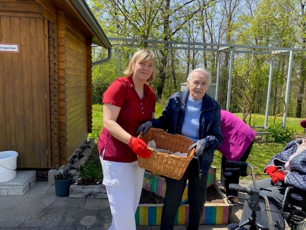 Andrea Weber hält gemeinsam mit Bewohnerin einen Korb mit Kartoffeln.