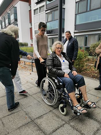 Pflegedirektorin schiebt Frau mit Rollstuhl